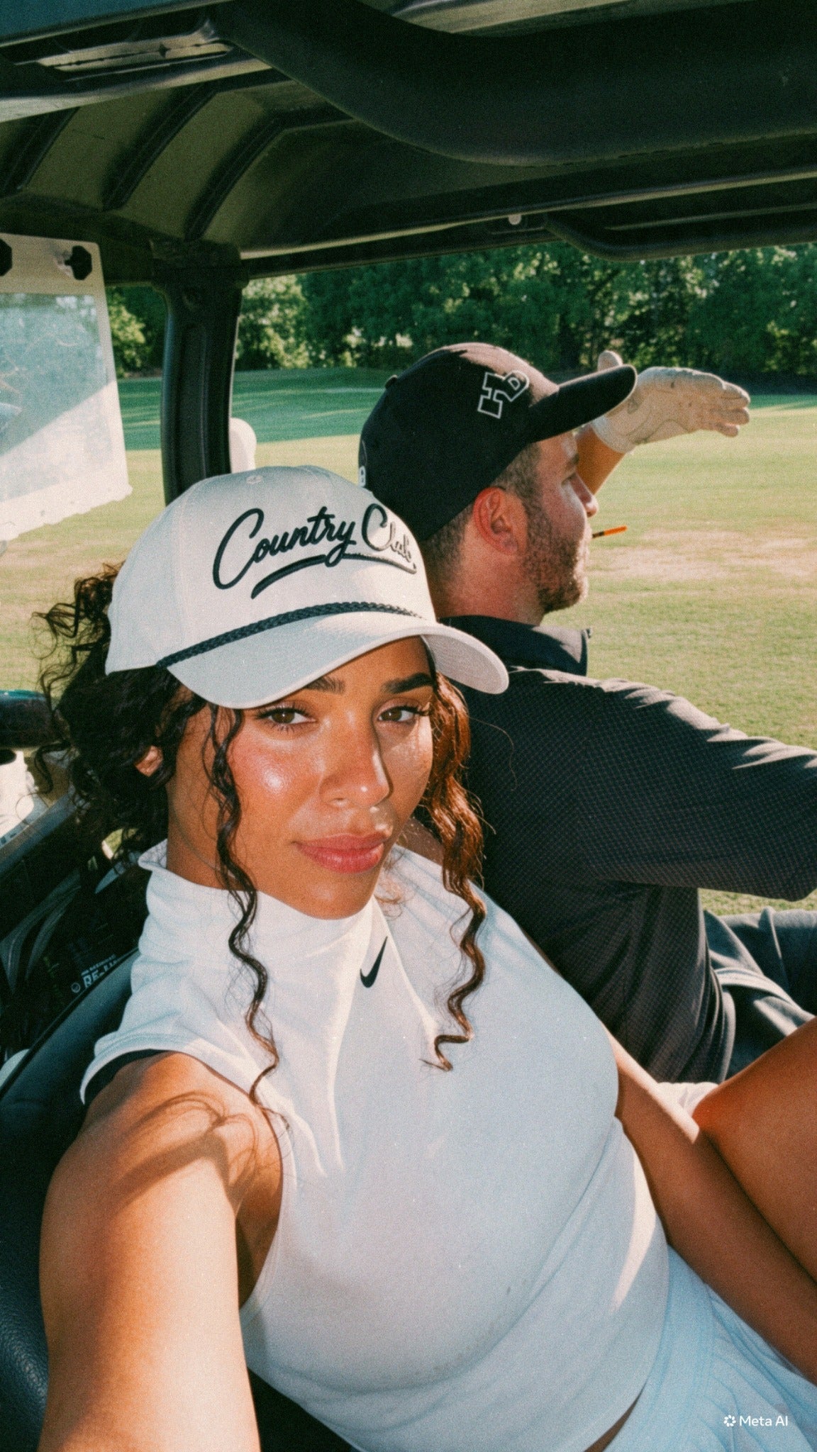 Destenee wearing a white Country Club rope hat in a golf cart